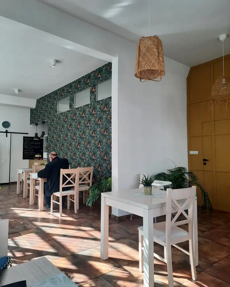 Stolik przy oknie, tapeta w liście i lampa z wikliny